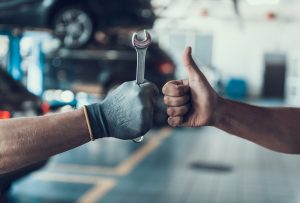 Close-up Thumb Up and Mechanics Hand with Tool. Automobile Master Wearing Gloves Showing Positive Gesture after Finishing Work. Technic occupation. Automobile Repair Service Concept | Greenwich, CT