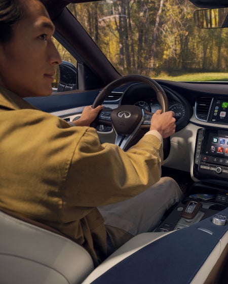A man using voice commands in an INFINITI vehicle with Alexa Access on the dashboard.
